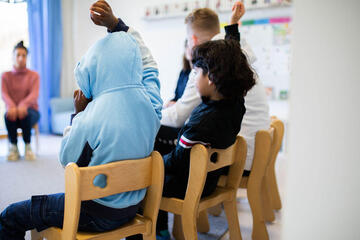 Mehrere Kinder sitzen gemeinsam im Morgenkreis zusammen