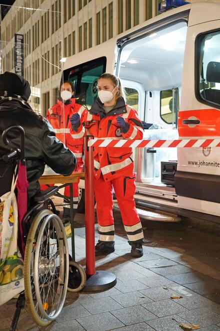 Helfer verteilen Essen an einen Obdachlosen im Rollstuhl