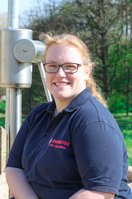 Eine Frau mit Johanniter-Polo-Shirt im Grünen