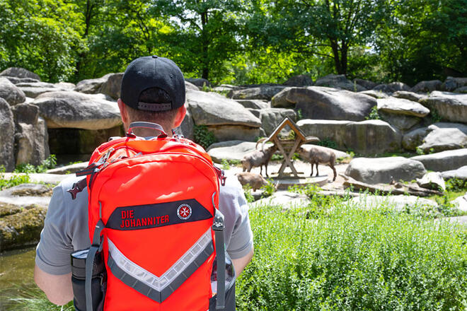 Ein Johanniter steht vor einem Tierparkgehege.