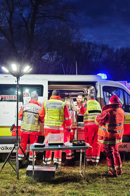 Einsatzkräfte stehen vor einem Rettungswagen.