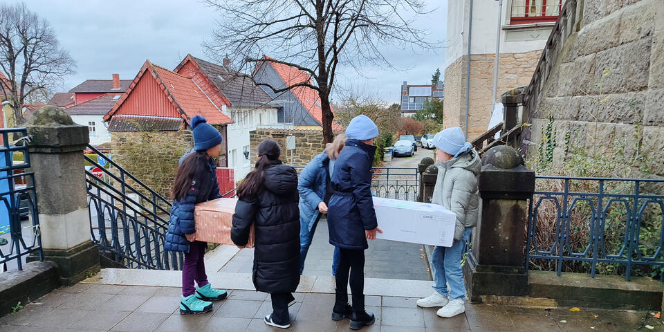 Kinder tragen Pakete eine Treppe hinab.