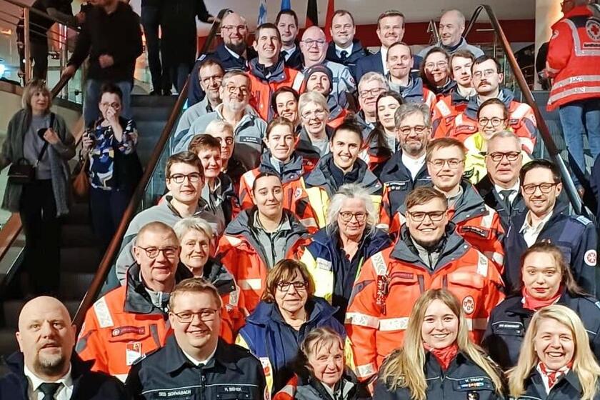 Eine große Gruppe von Johannitern teilweise in Einsatzkleidung hat sich auf einer Treppe für ein gemeinsames Gruppenfoto postiert.
