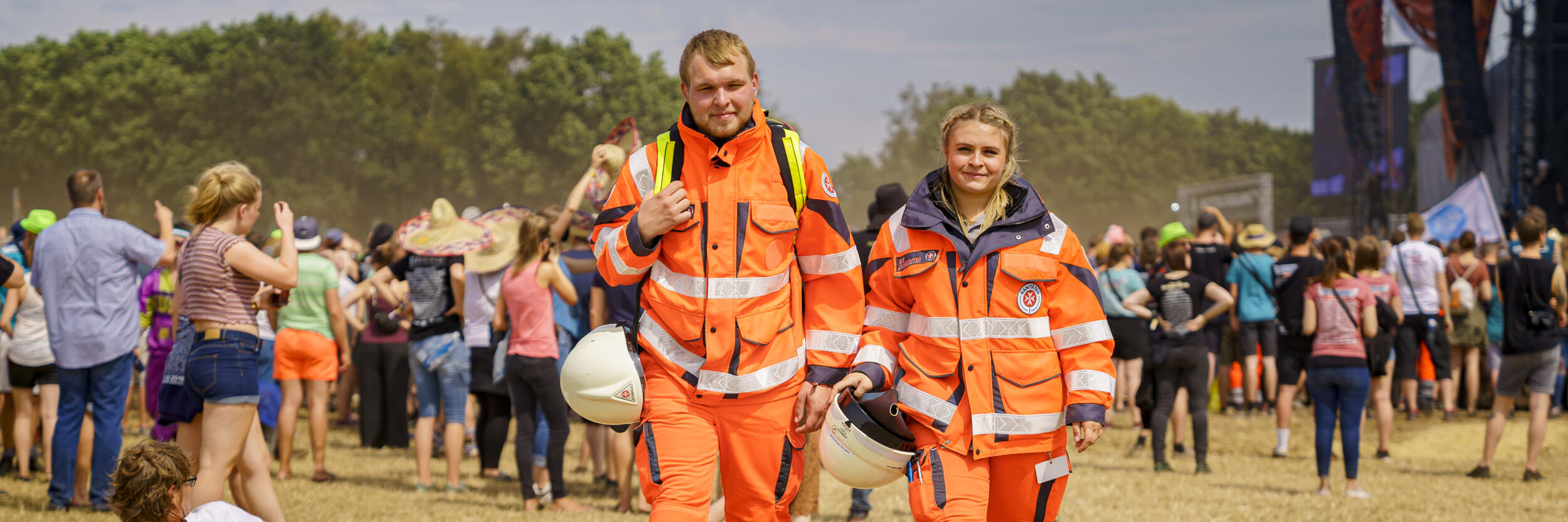 Zwei Mitarbeitende im Sanitätsdienst spazieren über ein Festivalgelände