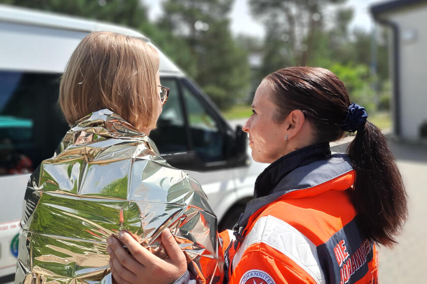 Eine ehrenamtliche Krisenhelferin des PSNV spendet einer Frau Trost.