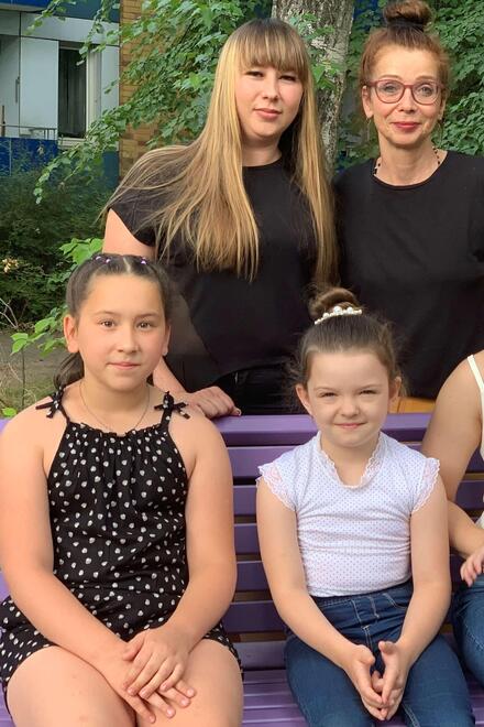 Eine Familie aus 6 Frauen und einem Baby, die auf einer Bank sitzen 