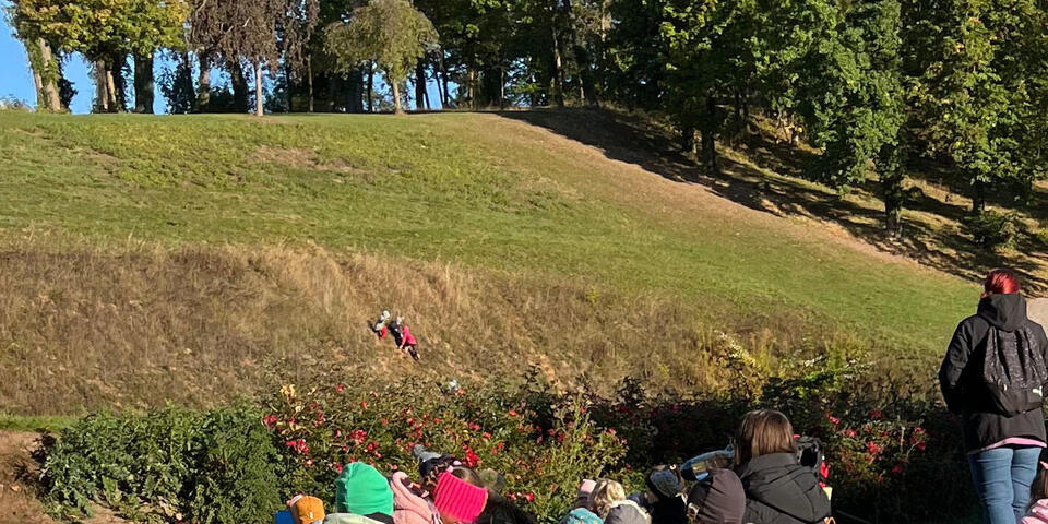 Kinder und Erwachsene sitzen auf einem Rasen