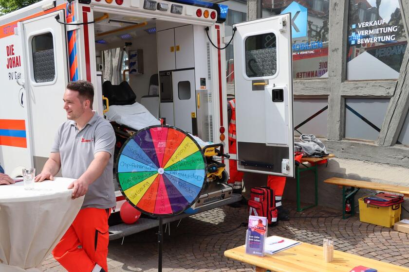 Kollege am Informationsstand der Johanniter am Maimarkt mit RTW und Glücksrad
