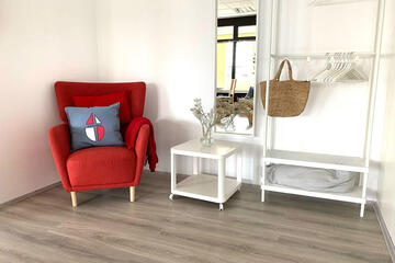 Der Eingangsbereich im Begegnungsraum Liederbach mit einem roten, gemütlichen Sessel zum ausruhen oder stillen.