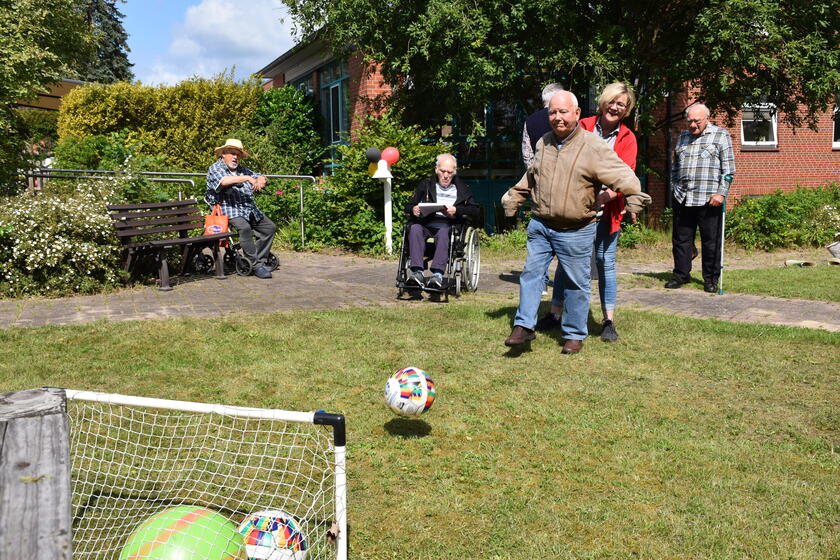 ein Gast der Tagespflege schießt einen Fußball ins Tor