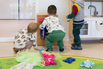Drei Kinder spielen gemeinsam mit einer Spielzeugküche