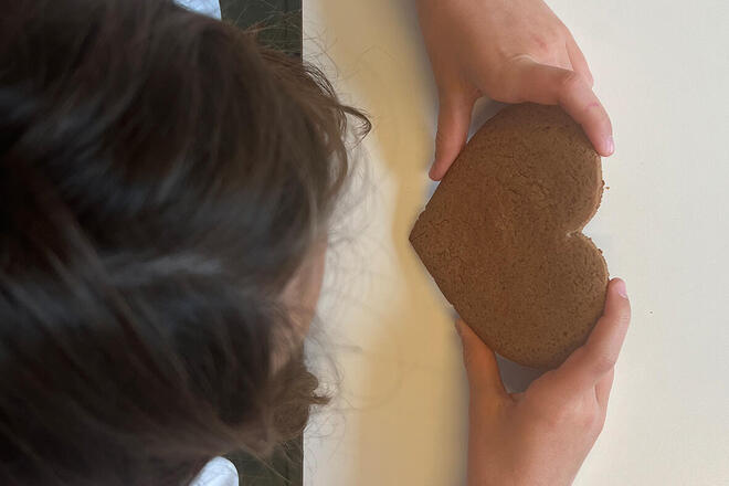 Ein Kind hält ein noch nicht dekoriertes Lebkuchenherz in der Hand.