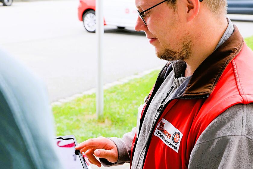 Mitarbeitender der Johanniter spricht mit potenziellem Fördermitglied.