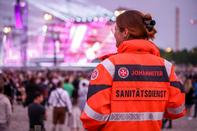 Johanniter-Sanitäterin sichert Großveranstaltung am Abend mit Blick auf die Bühne
