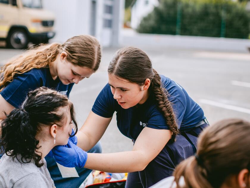 Schülerinnen kümmern sich um eine verletzte Person auf dem Schulhof