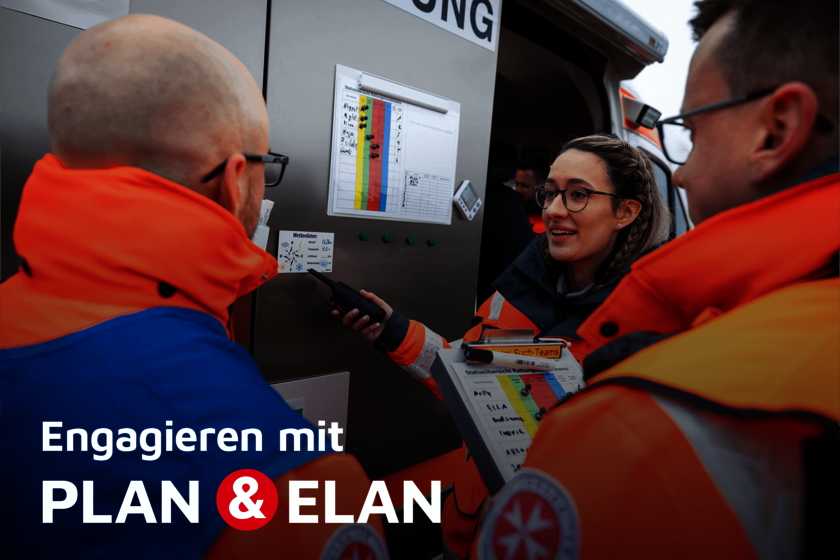Drei Einsatzkräfte in heller Einsatzkleidung besprechen einen Einsatzplan an einem Rettungsfahrzeug, eine Frau mit geflochtenen Haaren spricht ins Funkgerät und hält ein Klemmbrett mit farbiger Statusübersicht.