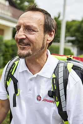 Mitarbeiter Bundesfreiwilligendienst auf dem Weg zum Kunden. Equipment im Rucksack auf dem Rücken