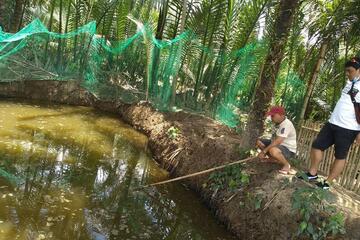 Ein Mann mit einem Kescher und ein weiterer Mann neben dem Teich