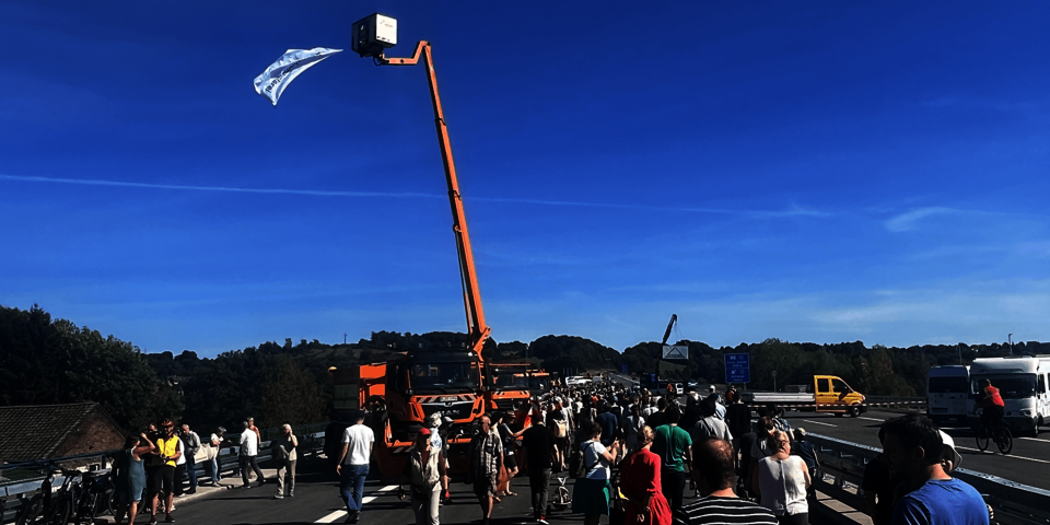 Spaziergänger auf einer Autobahnbrücke; im Hintergrund ein Baukran