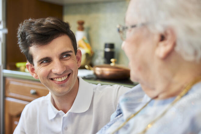 Ein Mitarbeiter der Johanniter unterhält sich mit einer Seniorin.