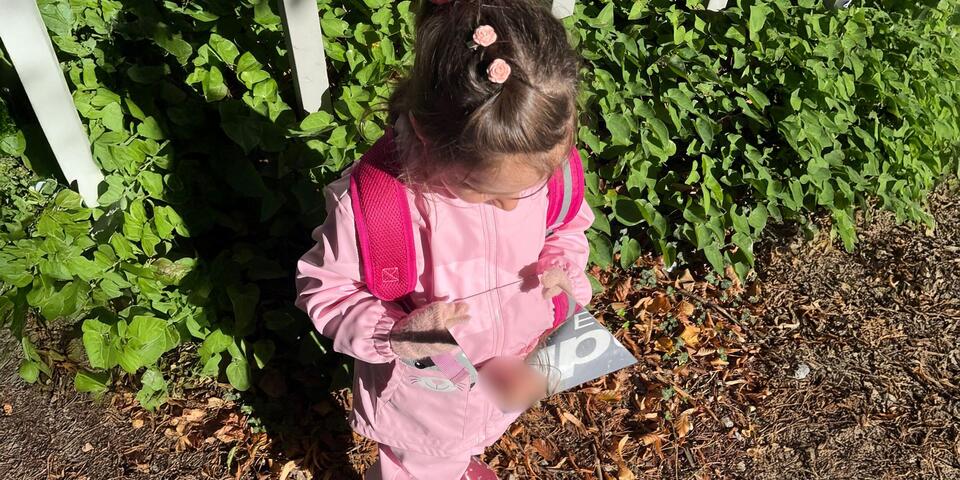 Ein Mädchen schaut in einen Taschenspiegel in ihrer Hand.