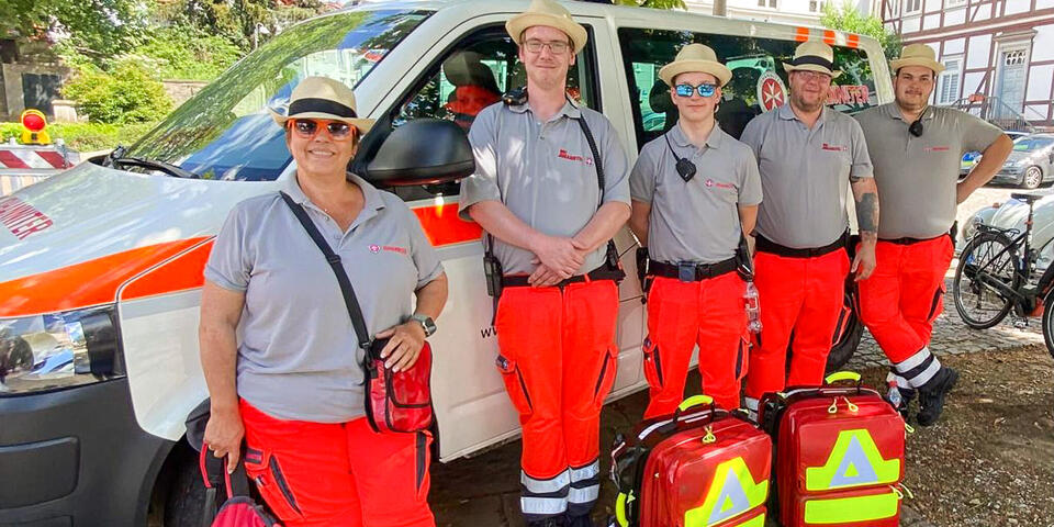 Fünf Johanniter und Johanniterinnen vor einem Einsatzfahrzeug