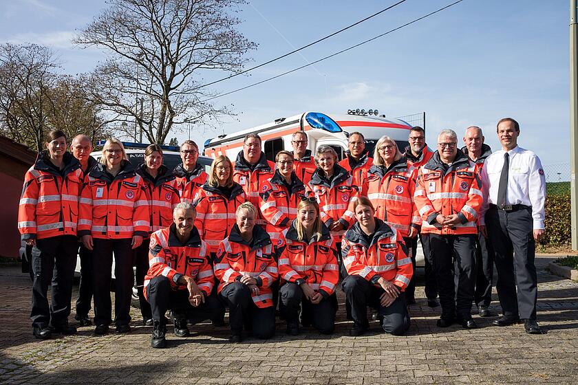 Gruppenbild mit 30 Personen in roten Johanniter‑Jacken im Freien.