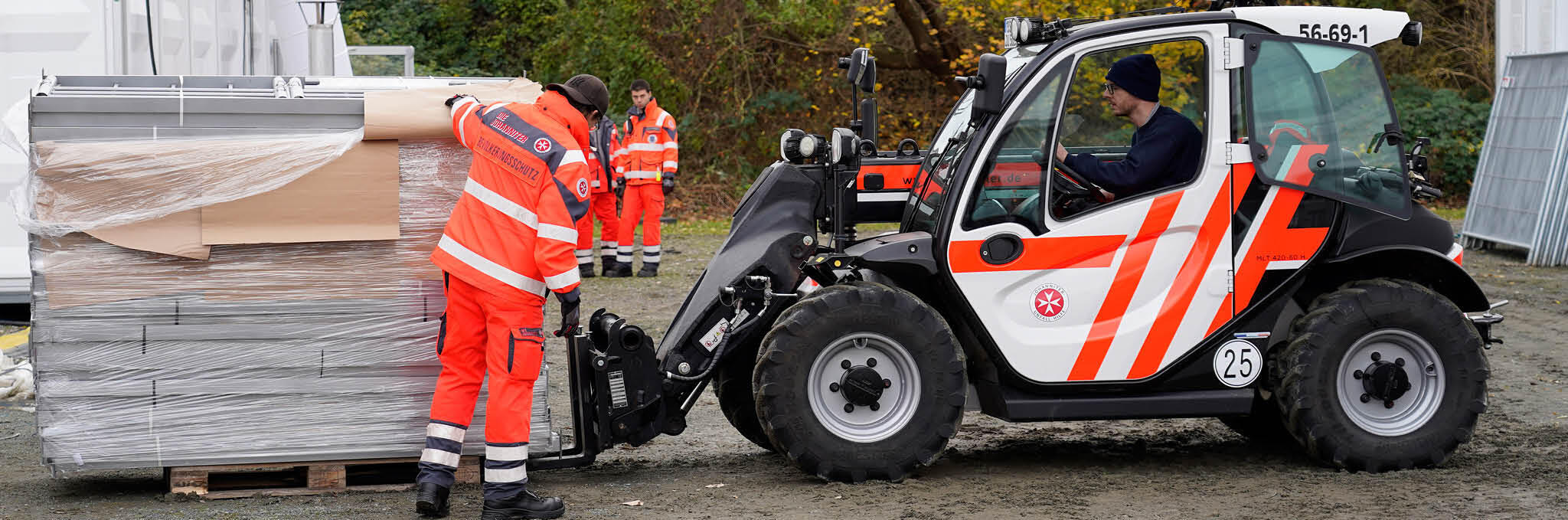 Eine Person hilft Material auf einem Johanniter-Ladekran festzumachen