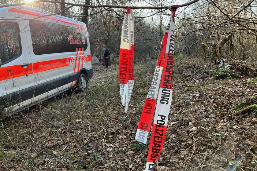 In einem Waldstück steht ein Johanniter-Transporter, daneben ist ein Absperrband zu sehen.