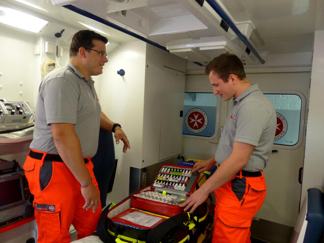 Blick in einen Rettungswagen, in dem sich der Rettungsdienstleiter und ein Azubi unterhalten.