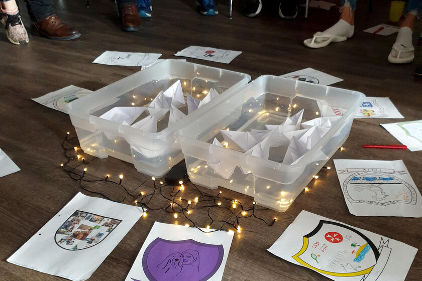 Verschiedene Zettel auf dem Boden. In der Mitte leigen zwei Kisten, um die eine Lichterketter liegt.