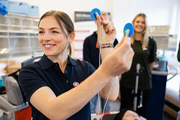 Eine Trainerin der Johanniter hält zwei EKG-Elektroden in die Luft.