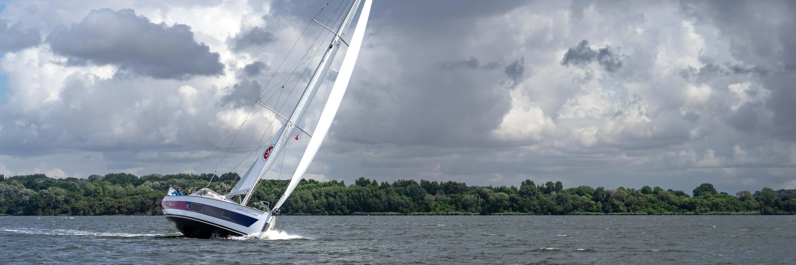 Segelboot der Johanniter mit gesetzten Segeln auf der Pötenitzer Wiek bei Travemünde.