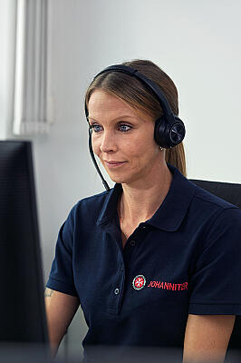 Johanniterin mit Headset am Arbeitsplatz