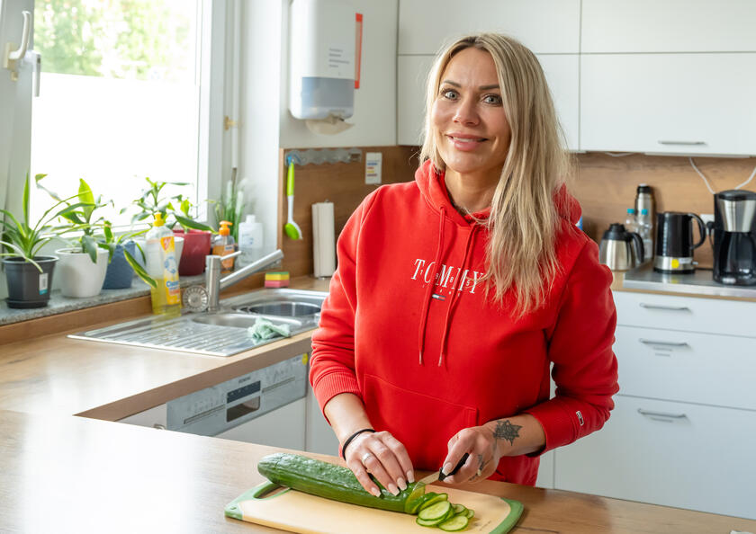 Eine Frau schneidet eine Gurke an einem Schneidebrett in der Küche