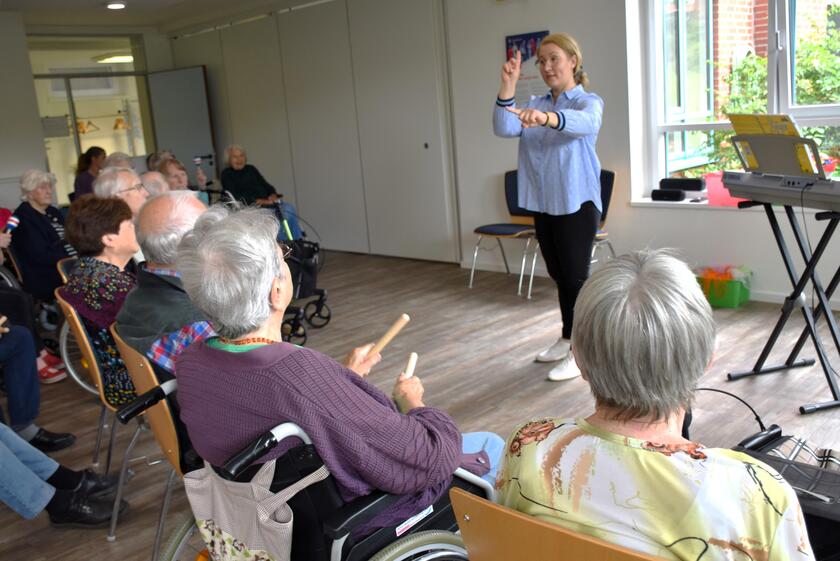 die Leiterin der Musikschule leitet die Gäste der Kurzzeitpflege und Tagespflege beim Singen und Bewegen an