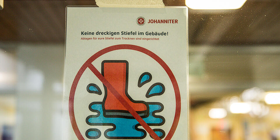 Schild an Helferunterkunft mit der Aufschrift: "Schuhe bitte draußen ausziehen"