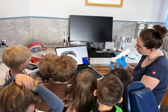 Begeisterte Kinder schauen Zahnärztin zu 