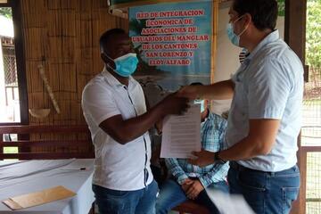 Der Vetreter des Umweltministeriums, Fernando Moya, übergibt das Abkommen an den Präsidenten von APESARBIPAR, Jackson Cabezas.