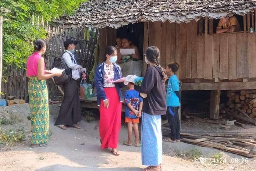 Eine Gruppe Menschen verteilt Flyer, alle tragen eine Mund-Nasen Bedeckung