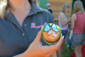 Ein bunt verzierter Cupcake wird in die Kamera gehalten