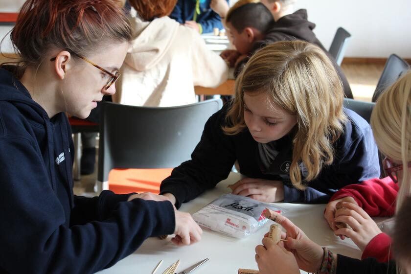 Eine Jugendgruppenleiterin erklärt einem Kind Erste Hilfe