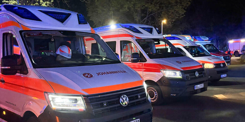 Johanniter-Einsatzfahrzeuge in der Nacht auf einem Parkplatz