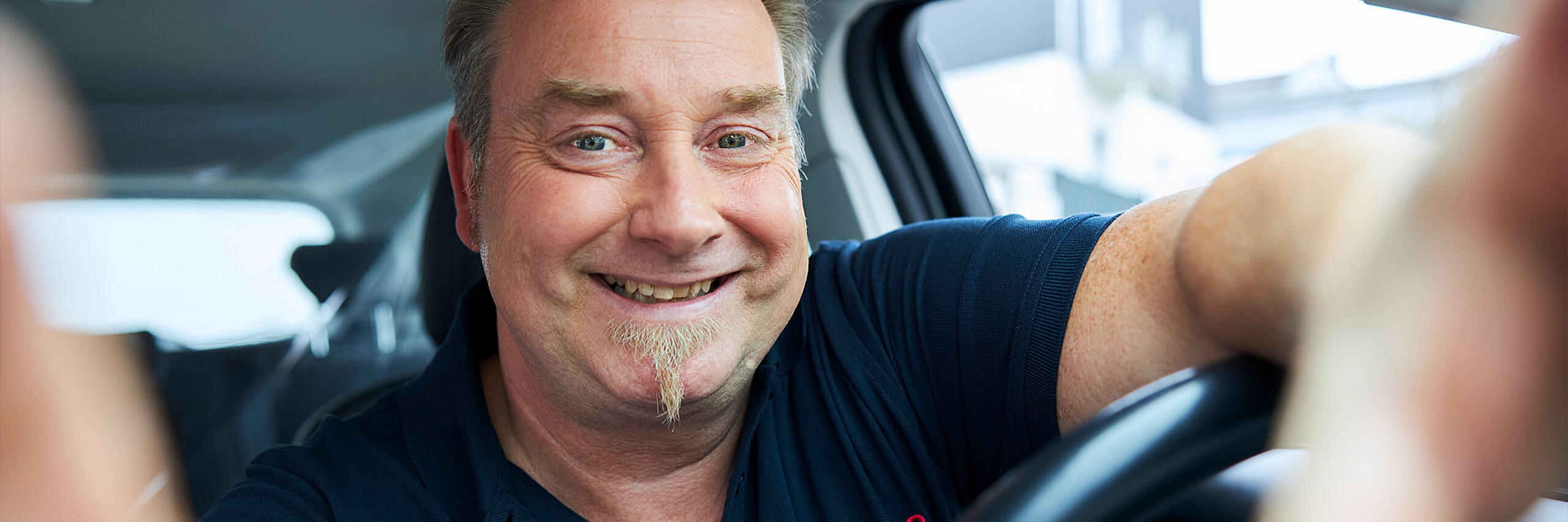 Ein Mitarbeiter der Johanniter sitzt in einem Auto.