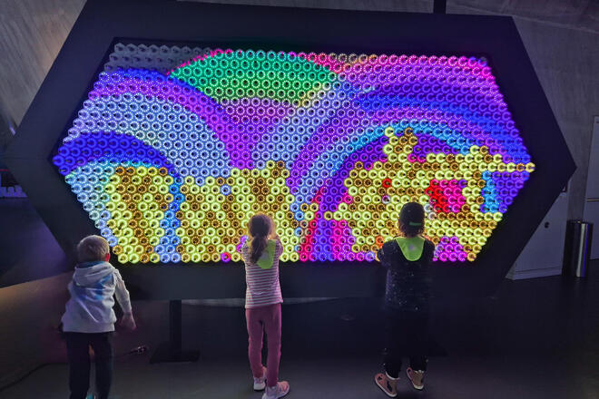 Kinder vor einem großen bunten Lichtexponat