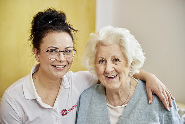 Mitarbeiterin Pflegedienst und Seniorin lächeln 
