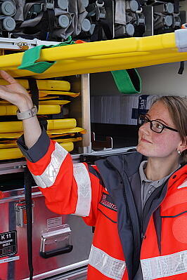 Eine Mitarbeiterin der Johanniter hebt eine Rettungstrage aus dem Gerätewagen.