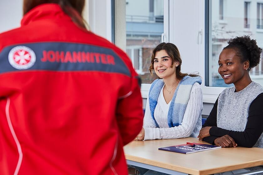 Zwei Teilnehmende eines Lehrgangs an der Johanniter-Akademie lassen sich von der Dozentin etwas erklären