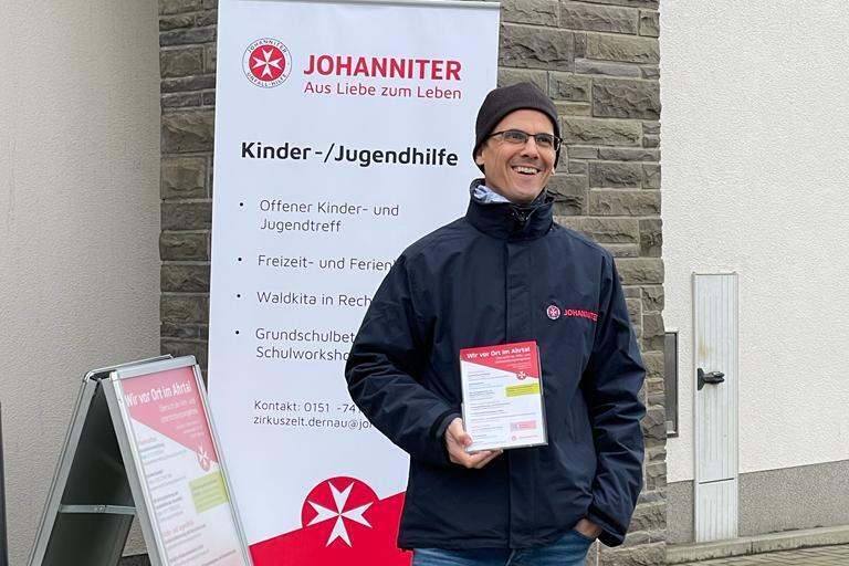 Ein Mitarbeiter mit Mütze am Infostand der Johanniter Info-Bus-Tour im Ahrtal.
