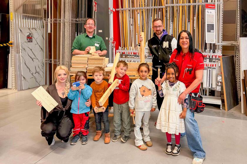Eine Gruppe Kinder, drei Erzieher*innen und ein Mitarbeiter von hagebaumarkt lächeln in die Kamera.